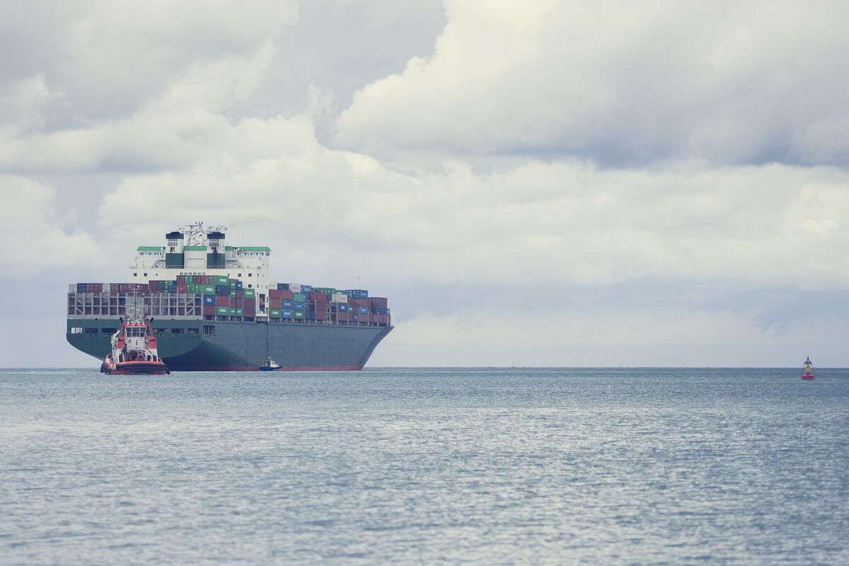 A container ship being guided by a tugboat on a calm sea